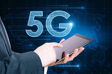 İş adamının eli bulanık arkaplanda parlayan 5G hologramla tableti işaret etsin. Kablosuz internet ve web hızı kavramı