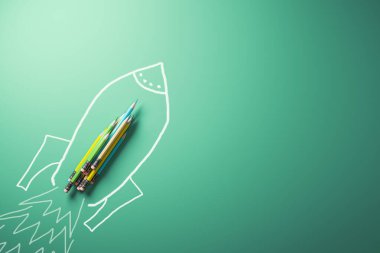 Yeşil arka planda modern kurşun kalemler ve roket uzay gemisi çizimi. Reklamınız için bir yer ayarlayın. Eğitim, okul ve bilgi kavramı. 3B Hazırlama