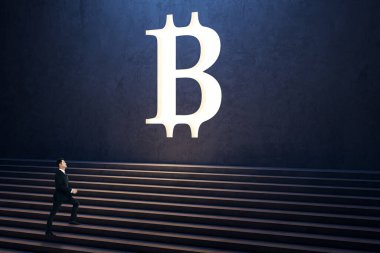 Duvardaki beyaz bitcoin tabelasına çıkan düşünceli genç adamın yan görüntüsü. Kripto para birimi ve başarı kavramı