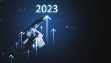 Tonlanmış işadamları koyu arkaplanda 2023 'e doğru büyüyen okları işaret ediyorlar. Şirket büyümesi, yıllık rapor ve artan kavram
