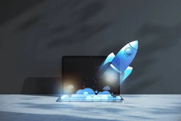 Close up of laptop at workplace with glowing flying blue rocket on concrete wall background. Start up and launch concept. 3D Rendering