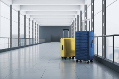 Seyahat, rezervasyon ve tatil konsepti mavi ve sarı valizlerle beton zeminde boş havaalanı koridorunda cam duvarlar ve arka planda gri giriş. 3B görüntüleme