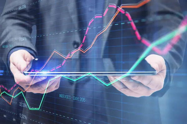Close up of businessman hand holding tablet with creative business graph with index and grid on blurry background. Stock market and financial statistics concept. Double exposure