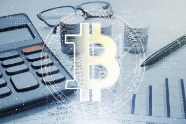 Bitcoin sembolü bir ofis masasının üzerinde hesap makinesi, kalem, bozuk para ve finansal belgelerle birlikte. Kripto para, finans ve teknoloji kavramı