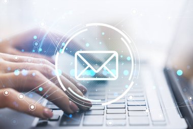Eller bulanık bir arkaplanda dijital bir ağ ile bağlanmış, ışıldayan bir e-posta simgesi içeren bir dizüstü bilgisayarda yazı yazıyor. Sanal iletişim kavramı