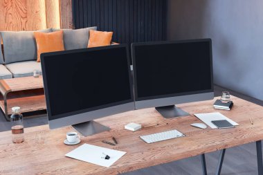 Ahşap masanın üzerinde iki boş bilgisayar ekranı olan modern çalışma alanı modeli, arka plandaki ofis odasında, temiz sunum tasarımı için ayarlanmış. 3B Hazırlama
