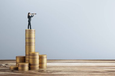 Teleskobu olan iş kadını, tahtadan yüzeydeki altın para yığınları, hafif arka plan, finansal vizyon ve iş dünyası başarısı kavramının üzerinde duruyor.