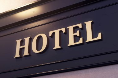 Koyu arkaplanlı koyu altın harfli otel tabelası, gerçekçi 3D renderleme tarzı, yukarıdaki sıcak ışık. Giriş işareti tasarımı kavramı