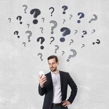 Kendine güvenen iş adamı, kafasının üstünde elle çizilmiş soru işaretleriyle telefonu tutuyor. Işık duvarı arkasında duruyor, merak kavramı.