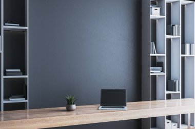 Minimalist modern ofis, ahşap masa, dizüstü bilgisayar, saksı fabrikası, ve koyu duvar arka planında inşa edilmiş raflar. Işık ve uzay kavramı. 3B Hazırlama