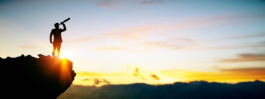 Gün doğumunda teleskopla dağın tepesinde sıcak ışık ve gökyüzü arkaplanı, vizyon ve liderlik kavramına sahip iş adamı silueti.