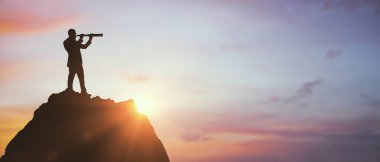 Bir dağın tepesinde teleskop kullanan bir iş adamının silueti, doğal gündoğumu arka planı, vizyon, liderlik ve hedef belirleme kavramı