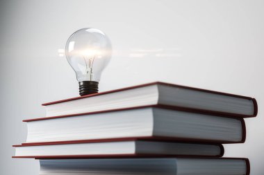 Hardcover kitaplarının üzerine parlayan ampul, beyaz arka planda gerçekçi bir tarz. Eğitim, eğitim ve yaratıcı fikirler kavramı. 3B Hazırlama