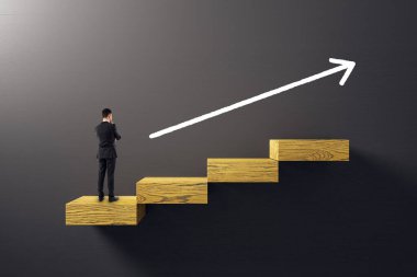 Takım elbiseli bir adam tahta basamaklarda duruyor, yukarı doğru ok, karanlık arka plan, kariyer gelişimini, yönü ve başarıyı simgeliyor.