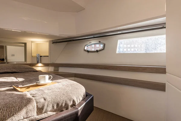 Interior of a luxury yacht bedroom with bed and coffee cup. Nobody inside