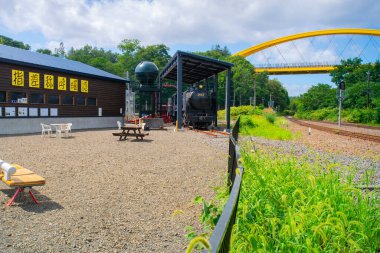 Niseko, Hokkaido, Japonya - 22 Ağustos 2023 - Niseko Köprüsü sahnesi, Hakodate Ana Hattı ve Shiribetsu Nehri üzerinden geçen sarı köprü, Niseko 'nun kuzeyi ve güneyine bağlanıyor.