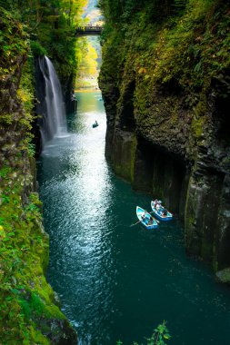 Takachiho Gorge, a narrow chasm cut through the cliff of volcanic basalt columns by the Gokase River, with Minainotaki waterfall cascading down to the river below, Miyazaki, Kyushu, Japan clipart