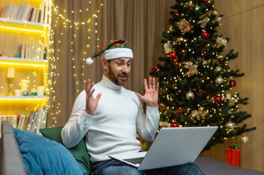 Adam Noel 'i ve yeni yılı evde tek başına kutluyor. Bilgisayarı video görüşmesi ve arkadaşlarıyla uzaktan iletişim kurmak için kullanıyor. Oturma odasındaki kanepede oturuyor..
