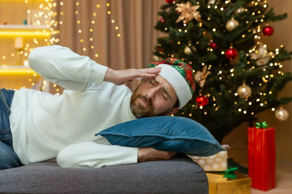 Man Trött Till Jul Nyårshatt Sover Han Vid Julgranen Soffan — Stockfoto