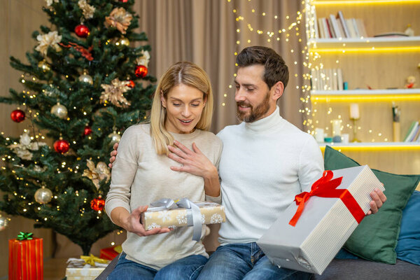 Middle aged couple exchanging gifts for christmas, family in love for christmas at home sitting on sofa at home.