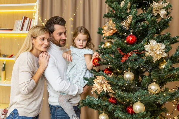 Christmas and new year family decorate tree, man woman and child daughter at home together in living room for new year smile and rejoice, happy family holidays.