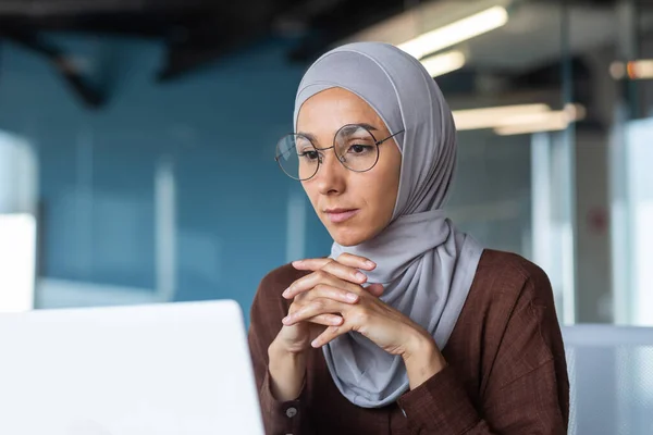 満足したビジネス女性のノートパソコン画面を見てのクローズアップ写真 現代オフィスビル内で働くヒジャーブのムスリム女性 意思決定について考える女性上司 — ストック写真