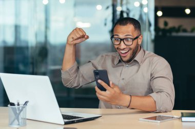 Modern ofis binasında çalışan başarılı Afro-Amerikan işadamı zaferi ve başarıyı kutlayan adam internet üzerinden iyi haberler aldı..
