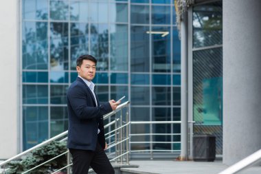 Genç yakışıklı bir Asyalı toplantıya gider, bir ofis merkezinde iş görüşmesi için. Elinde telefon ve belgelerle merdivenlerde duruyor, kameraya bakıyor..