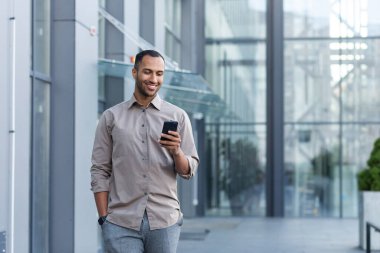 Yakışıklı, Latin kökenli, Afro-Amerikan bir adam caddede bir ofis merkezine doğru yürüyor. Sol elinde bir telefon tutuyor, sağ eli de cebinde. Kullanıyor, haberleri okuyor, gülümsüyor..