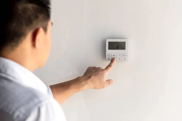 stock image Close-up photo. The finger of a mans hand in a white shirt includes the buttons of the control panel of the air conditioner on the wall of the house, office.