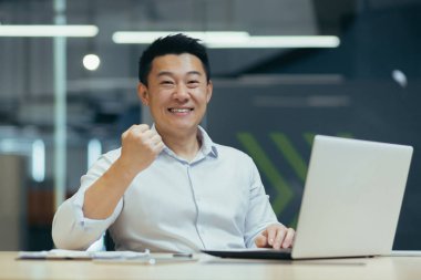 Masasında dizüstü bilgisayarla oturan Asyalı bir öğrenci üniversiteden iyi haberler almış. Sınavı geçtim, üniversiteye girdim. Kameraya sevinçle bakar, muzaffer bir jest gösterir..