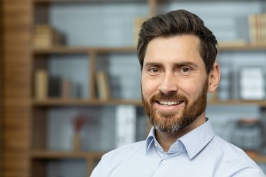 Close up businessman in shirt smiling and looking at camera, successful man inside office satisfied with achievement results, mature investor financier headshot.