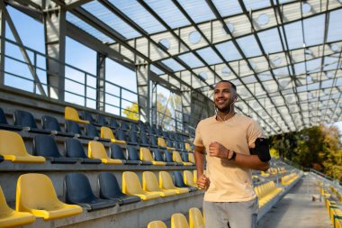 Sabahları stadyumda koşuşturan kulaklıklı genç İspanyol bir adam. Erkek, telefondaki uygulamayı kullanarak müzik ve ses kitapları dinliyor. Günlük antrenmanlarda gülümsüyor ve mutluydu..