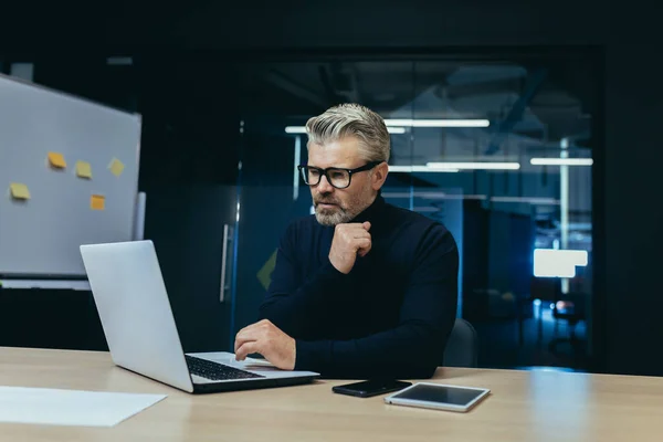 stock image Thinking businessman inside the office with a laptop, mature adult boss thinking about the decision for working sitting with a computer.