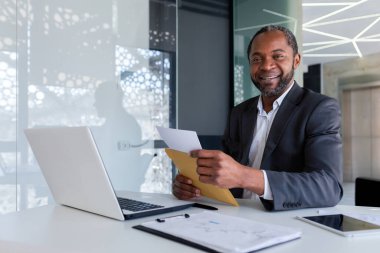İş yerindeki başarılı Afro-Amerikan iş adamı portresi ofis içinde yetişkin bir erkek gülümseyen ve kameraya bakan, patron posta zarflı bir mesaj aldı..
