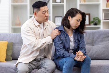 Aile psikolojik desteği, Asyalı çift koltukta oturuyor düşünceli bir kadın depresyondaki adamı rahatlatıyor ve destekliyor..