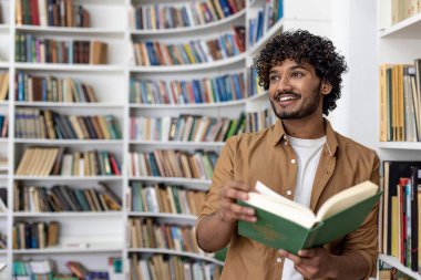 Akademik bir üniversite kütüphanesinde kitap okuyan genç İspanyol öğrenci, mutlu bir şekilde pencereye doğru gülümsüyor..