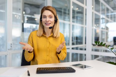 Webcam görüntüsü, gülümseyen ve kameraya bakan mutlu iş kadını iş arkadaşlarıyla video görüşmesi, uzaktan görüşme, modern ofiste gözlük takan kadın çalışan..