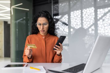 İş yerindeki İspanyol iş kadını üzgün ve hayal kırıklığına uğramış. Banka kartı ve telefonu tutan kadın. İnternet üzerinden alım yapmaya çalışırken aldatılmış..