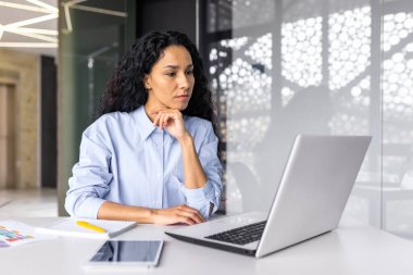 Beautiful indian woman programmer web developer focused and confident working on laptop writing code programming business woman worker in modern office working in casual clothes