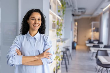 Kafe restoranında çalışan güzel bir kadının portresi kıvırcık saçlı ve gözlüklü bir kadının kollarını kavuşturup kameraya bakması.