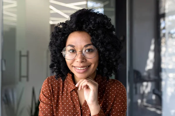 Close-up portrait of beautiful Latin American businesswoman smiling and looking at camera, working inside modern office.