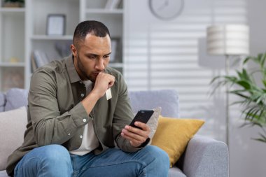 Genç bir Afrikalı Amerikalı kötü haber aldı, cep telefonundan bir mesaj. Evde üzgün bir şekilde kanepede oturur, şok içinde ekrana bakar..