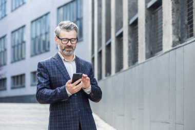 Başarılı, gri saçlı bir işadamı ofis binasının dışında telefon kullanır. Takım elbiseli kıdemli bir patron sokakta yürür. Bir adam mesajları okur ve internet sayfalarına göz atar..