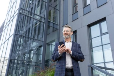 Takım elbiseli olgun bir adam telefonu kullanır, bir iş adamı elinde akıllı bir telefon tutar, mesajlar yazar ve internette sosyal ağlar kurar, patron haberleri okur, gülümseyen bir uygulama kullanıcısı....