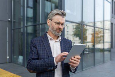 Ciddi ciddi iş adamlarının ofis binasının dışında tablet bilgisayar kullandığını, takım elbiseli patronun borsada finans haberleri okuduğunu, iş sahibinin şehir merkezinde yürüdüğünü düşünüyor..