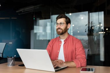 İş yerindeki gülümseyen hayalperest işadamı, deneyimli ve başarılı programcı mühendis gülümseyip pencereden dışarı bakıyor, iş yerindeki başarının sonuçlarından memnun..
