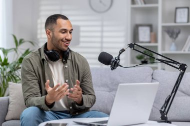 Genç İspanyol adamın küçük bir stüdyosu var. Kanepeye oturmuş, kulaklıkla bir yayın kaydediyor. İnternetteki bir videoyla mikrofon aracılığıyla iletişim kuruyor..
