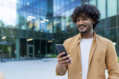 Genç bir Hintli ofis binasının önünde duruyor, bir gökdelen, ve bir telefon kullanıyor. Gülümsemeler, mesajlar, sohbetler, aramalar..