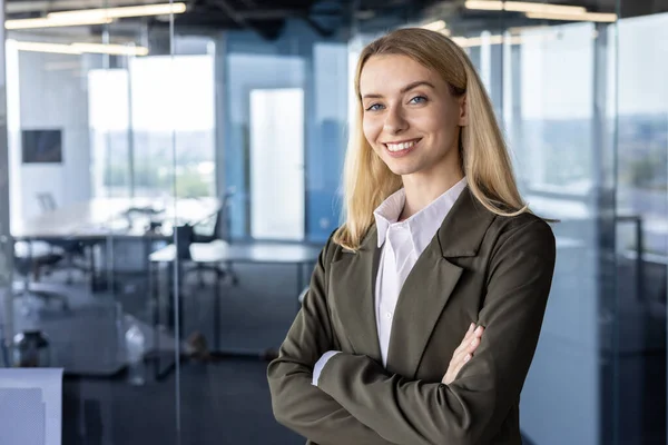 stock image Portrait of a successful and smiling business woman, the founder of the company, the director in a suit standing confidently in the office. crossing his arms on his chest, looking at the camera.